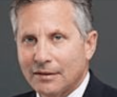Professional headshot of a middle-aged man with short gray hair