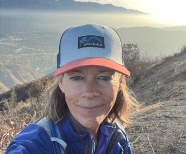 Hiker wearing a Patagonia cap smiles on a mountain trail