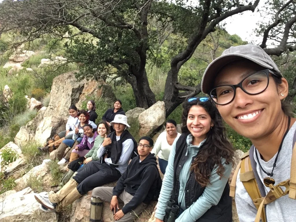 Group of diverse individuals on a rocky trail, smiling and posing for a selfie during a nature outing